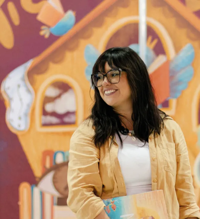 La ilustradora Anahí Echeverría frente a un mural ilustrado