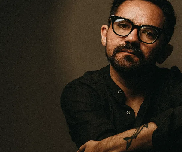 Ricardo Torres con lentes de pasta en un retrato de luz baja